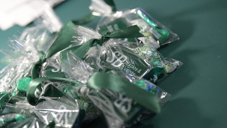 Dark green packages with SB logo in white wrapped with a green bow on an exhibit table